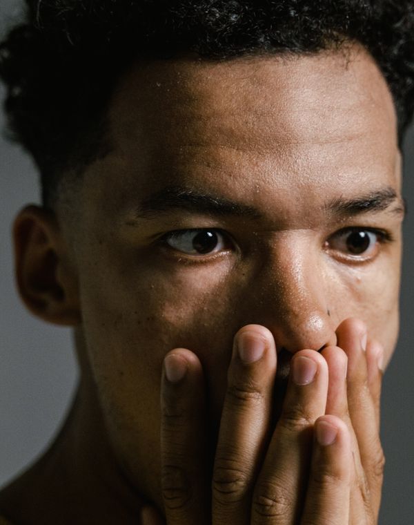 A man staring wide-eyed with his hands over his mouth
