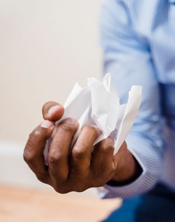 A fist crushing a sheet of paper
