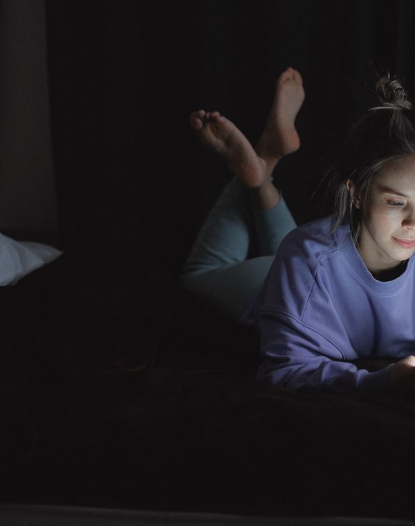 A woman scrolling her phone in bed in the dark