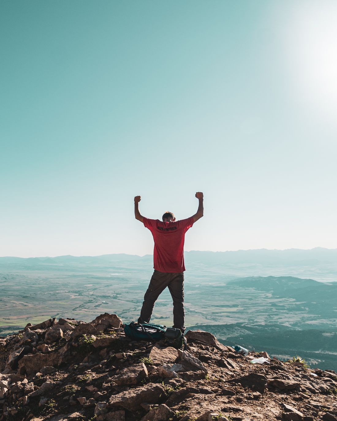 A man on a mountain summit with both fists raised in victory